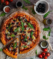 Fototapeta Domowa wegetariańska pizza na dyniowym spodzie, pizza z serem, mozarellą, oliwkami, ostrą papryczką i rukolą, pyszne danie, kuchnia włoska, restauracja, oliwa obraz