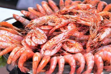 Grilled shrimps close up served on a plate on open kitchen on food festival event. Grill and cooking seafood. Сloseup.