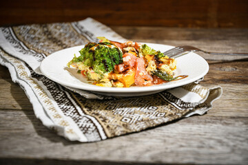 Dish, salmon with vegetables on a white plate on a kitchen napkin on a wooden dining table .. Home cooking.
