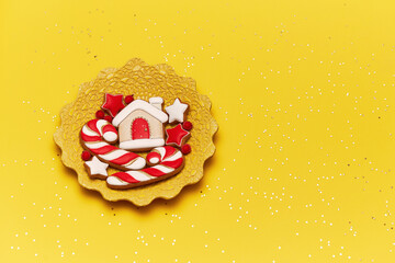 Christmas gingerbread cookies on a yellow handmade plate and yellow background. Copy space for text. Flat lay. Winter holidays background. 