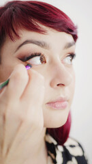 Face of a beautiful young girl while a make-up artist applies make-up on her eyes. Eye liner. Makeup in process.