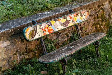 Wooden bench with colored backrest in a public park in Barga