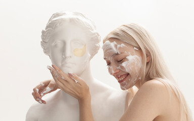 girl with makeup on her face posing with plaster sculpture on a light background