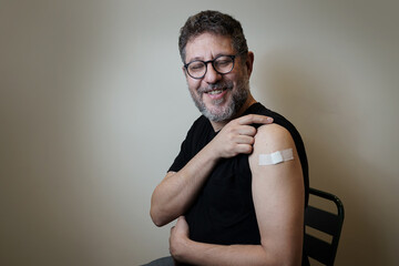 Vaccinated mature man showing the arm with the bandage