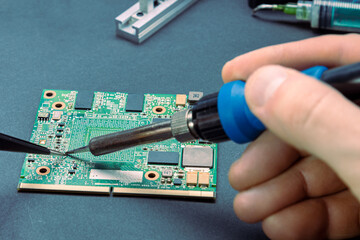 Male hands holding a soldering iron to solder the resistor on the board from the computer. repair...