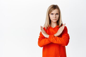 Teen blond girl showing cross, stop rejection gesture, prohibit smth, disagree, showing taboo...