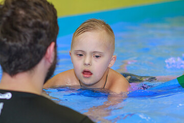 A boy with Down syndrome learns to swim in the pool, rehabilitation of disabled children, genetic...