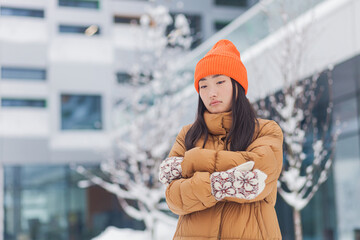 Asian woman on the street frozen in the cold, on a winter snowy day, waiting