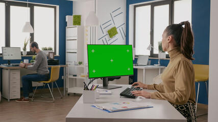 Woman using computer with isolated green screen at desk. Person working with chroma key and mock up...