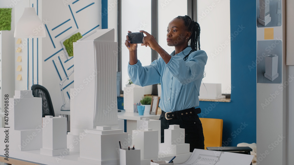 Poster woman engineer using smartphone to plan layout of building model and maquette. architectural employe