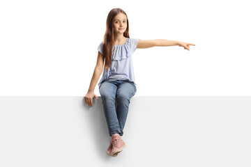 Girl sitting on a blank panel and pointing to the side