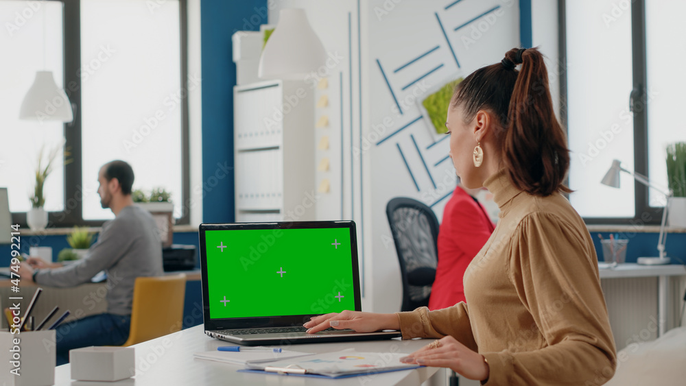 Aufkleber business woman using laptop with green screen in office. company worker looking at chroma key with i