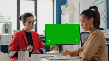 Women doing teamwork with isolated green screen on computer in business office. Workmates using...
