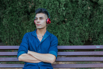 Young observer man sitting on a bench listening to music