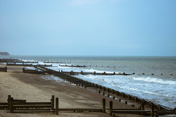 Fototapeta na wymiar Beach and sea with wooden piers in Norwich, Norfolk, UK