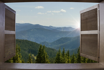 Window view of a mountains. Landscape. Sunny Day. Hotel room in the forest with a beautiful view. House in the mountain.
