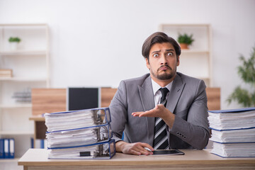 Young male employee unhappy with excessive work in the office