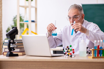 Old male teacher chemist in the classroom