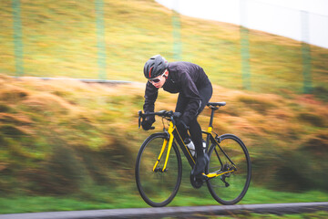 Fototapeta na wymiar Pan shot of a young caucasian cyclist man sprinting on his bike.