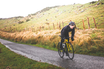 Young caucasian cyclist man climbing a hill in a foggy mountain.