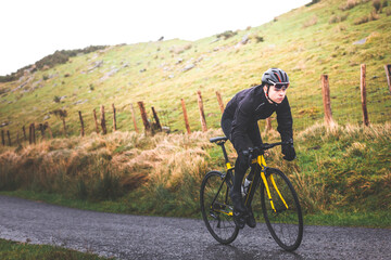Obraz premium Young caucasian cyclist man climbing a hill in a foggy mountain.