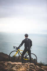 Young caucasian cyclist man at the top of the mountain looking to the sea.