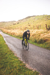 Fototapeta premium Young caucasian cyclist man climbing a hill in a foggy mountain.