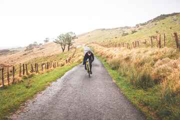 Obraz premium Young caucasian cyclist man sprinting while climbing a hill in a foggy mountain.