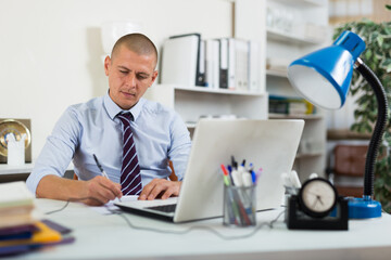 Professional business man using laptop at workplace in office