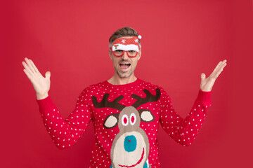 amazed man in winter sweater and party santa claus glasses. xmas guy