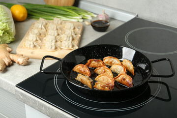 Cooking gyoza on frying pan with hot oil in kitchen
