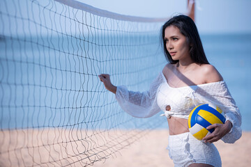 A female in white bikini on the volleyball court with blurred ocean background