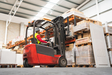 Caucasian male sitting on a forklift working in a warehouse - obrazy, fototapety, plakaty
