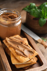 Crispy crackers with delicious meat pate on wooden table, closeup