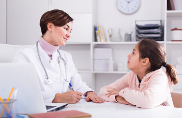 Pediatrician asks the girl about her health and fills patient's chart