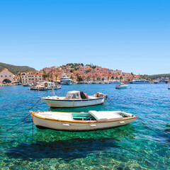 Colorful boats in the crystal clear water of Hvar harbor - obrazy, fototapety, plakaty