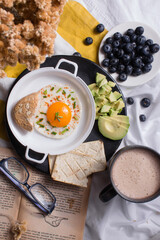 Healthy homemade breakfast with chocolate, fried egg with chives, toast, avocado and blueberries.
