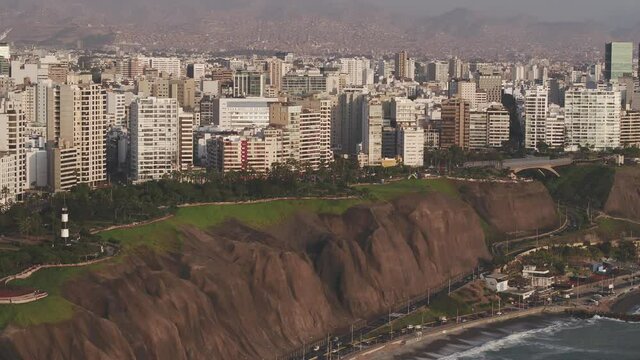 Panoramic  aerial view of Lima city, with deail of the cliff, the green coast and the poor towns of the hills  at the background.