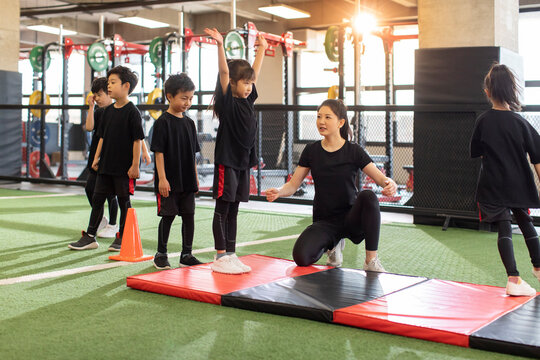 Active children having exercise class with their coach in gym