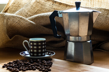 Coffee beans in a cup and Italian coffee maker on a wooden table in Brazil
