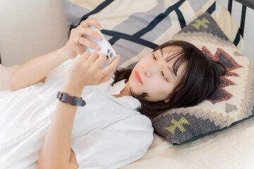 ベッドでスマホを使って動画を見る女性