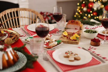 Festive dinner with delicious food and wine on table indoors. Christmas Eve celebration