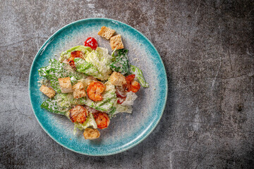 Healthy salad with fried shrimp, greens and croutons in a plate against a gray stone table. A healthy breakfast in a restaurant