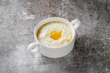 Rice porridge with butter in a white cup against a gray stone table. A healthy breakfast in a restaurant .