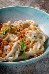 Meat dumplings with spices on a plate with greens against the background of a gray stone table