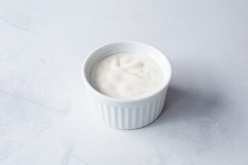A view of ranch dressing in a small plastic condiment cup.