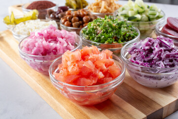 A view of several toppings inside glass cups on a wood board.