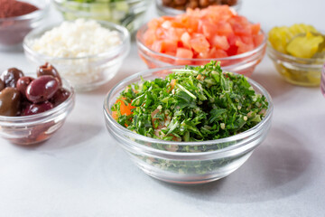 A view of a glass cup of tabbouleh, among other ingredients.