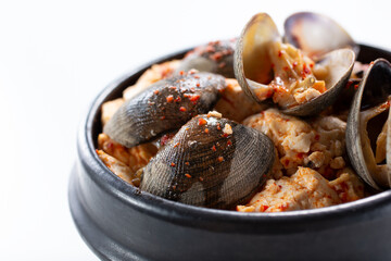 A closeup view of a bowl of Korean soft tofu soup, featuring clams.