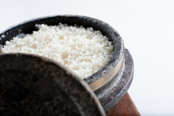 A view of white rice cooked inside a Korean stone pot. The stone lid is off to the side.